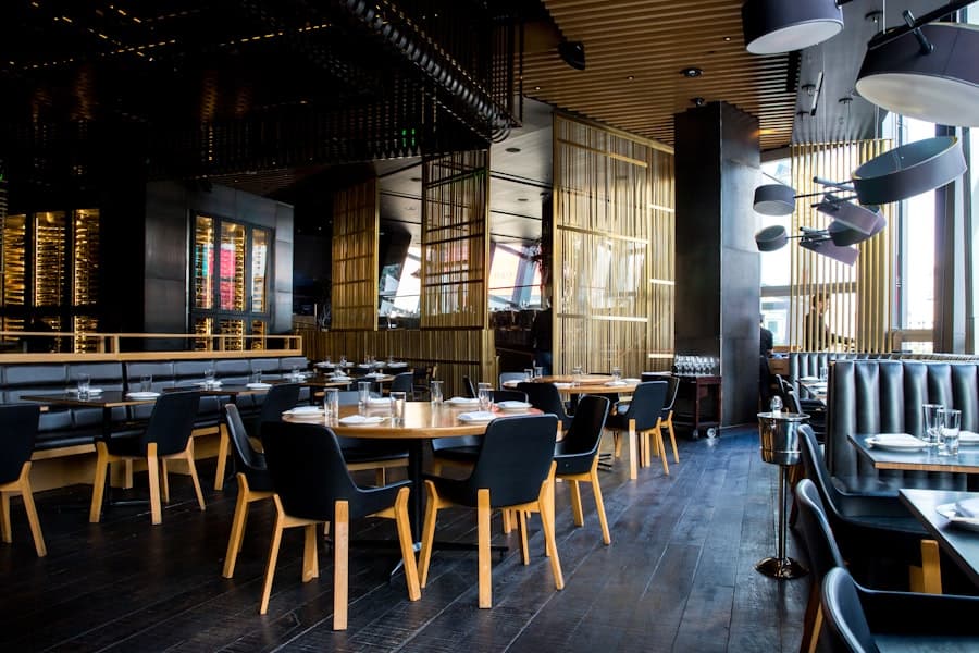 Restaurant dining room with dark wood tables, upholstered chairs and pendant lights