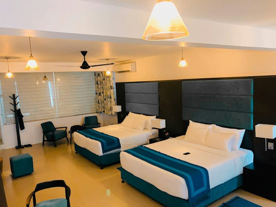Family room with two beds in blue and white linen, a ceiling fan and an armchair